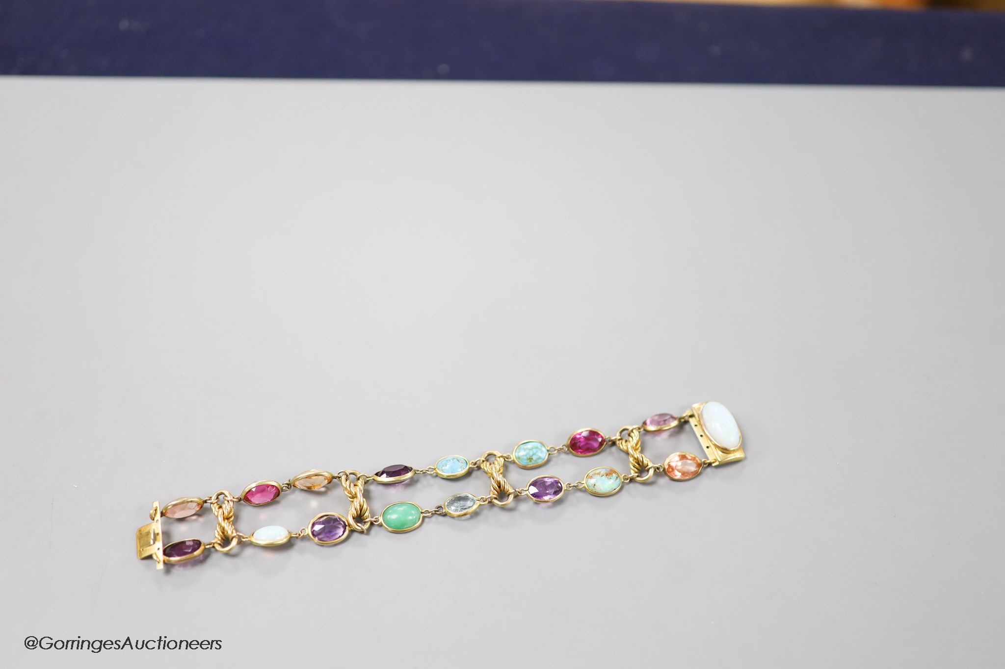 An early 20th century yellow metal and multi gem set bracelet, including white opal, turquoise, amethyst etc, 17cm, gross weight 30.3 grams.